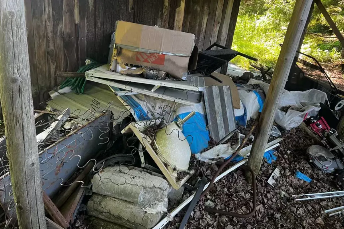 Before: Junk and scrap piled under a shed overhang