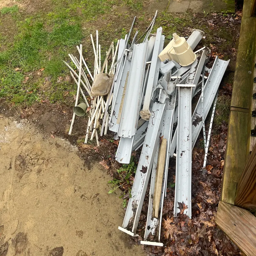 Before: Pile of old gutters and scrap beside a deck