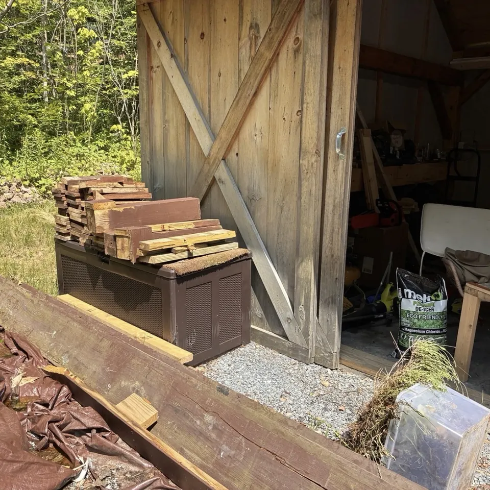 Before: Lumber and scrap stacked by a barn door